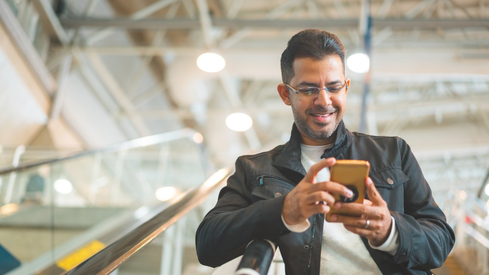 Man on phone online shopping while coming down the escalator.