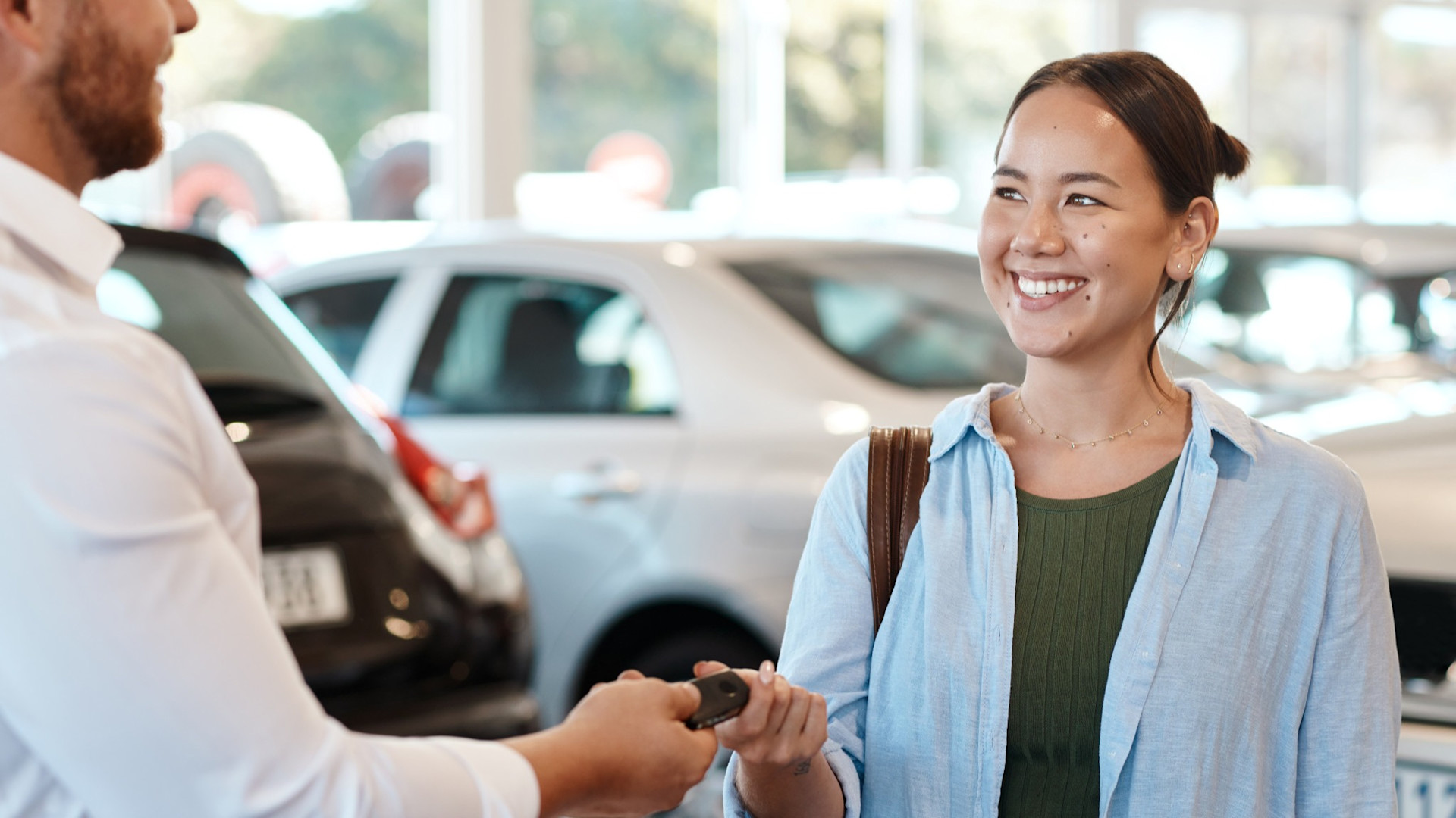 Happy first-time car buyer receiving vehicle keys at a dealership
