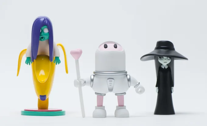 Three different character figures: a banana character, an astronaut, and a figure in a black hat