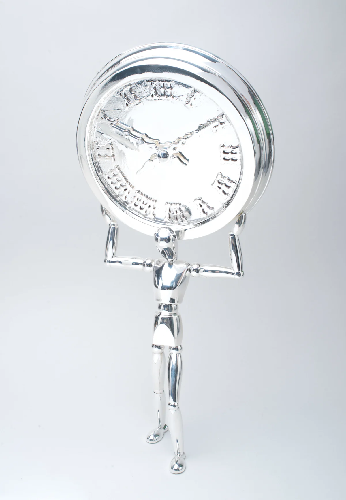 A silver clock held up by a slender figure