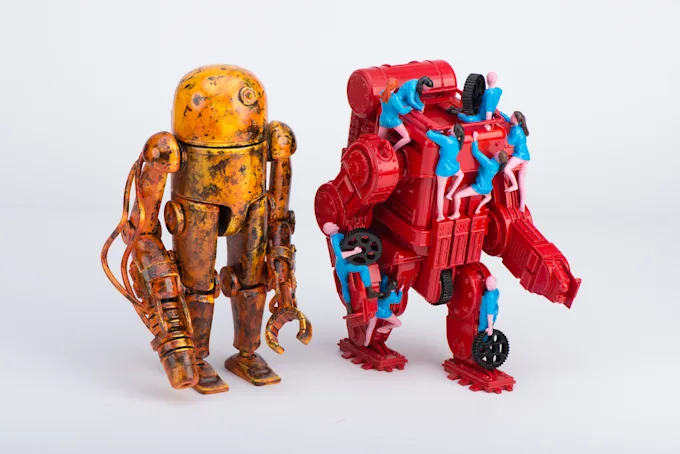 Two detailed robot figures, one with a weathered orange metal finish and one in red with blue details