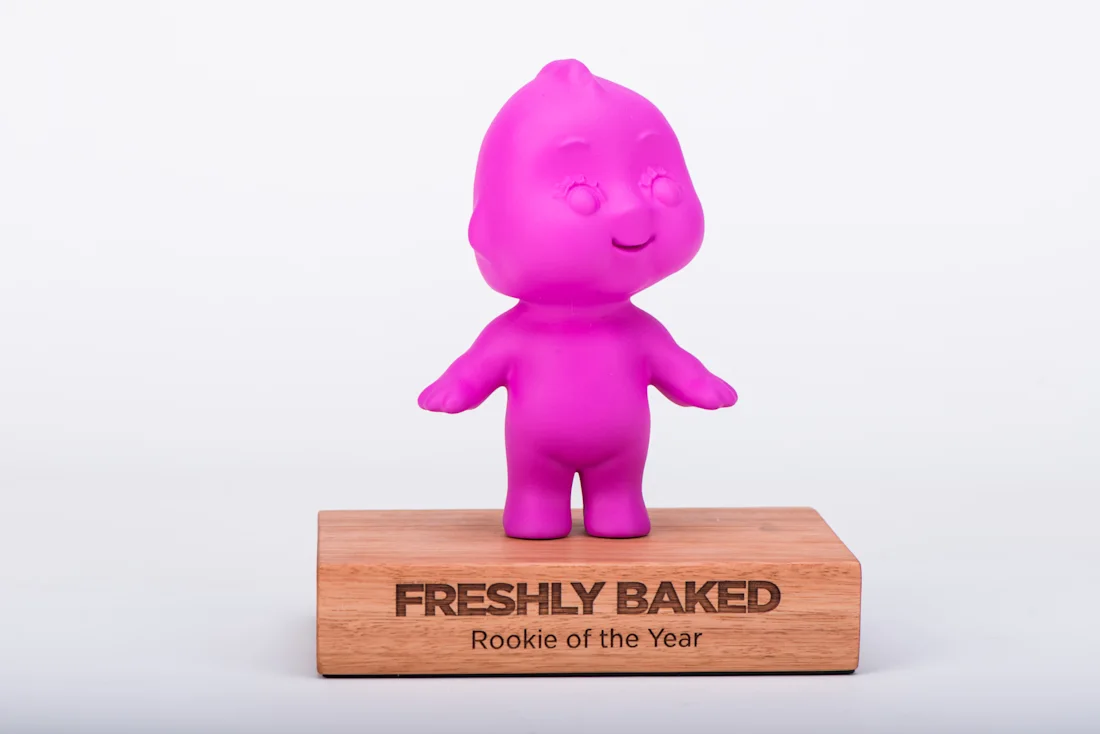 A pink baby figure on a wood base engraved Freshly Baked, Rookie of the Year