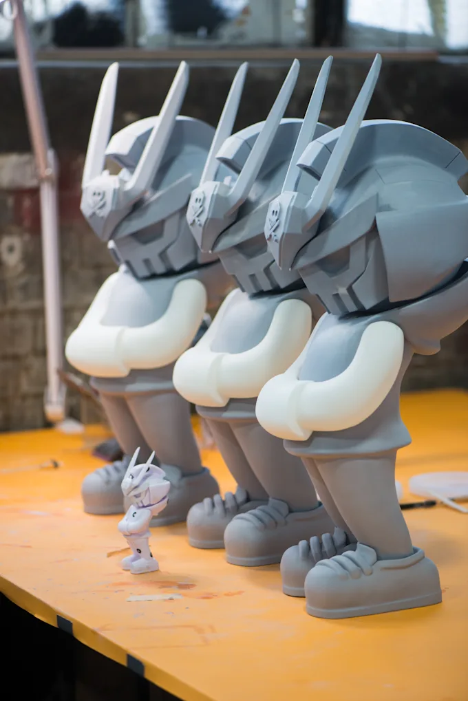 Three matching gray armored character figures lined up in the studio