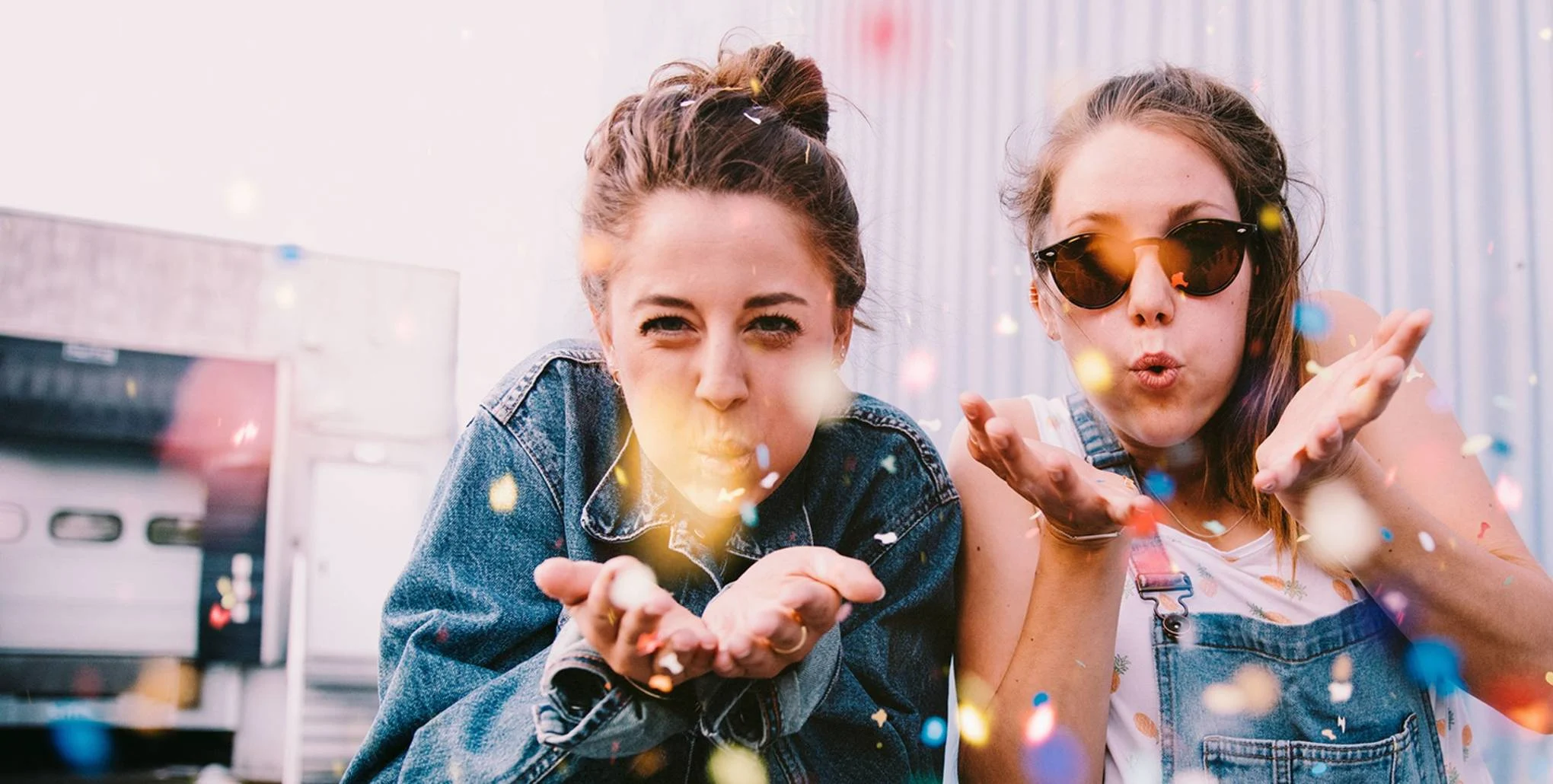 Zwei junge Frauen pusten Konfetti in die Luft. Alle Young Adult Jugendbücher bei Bastei Lübbe