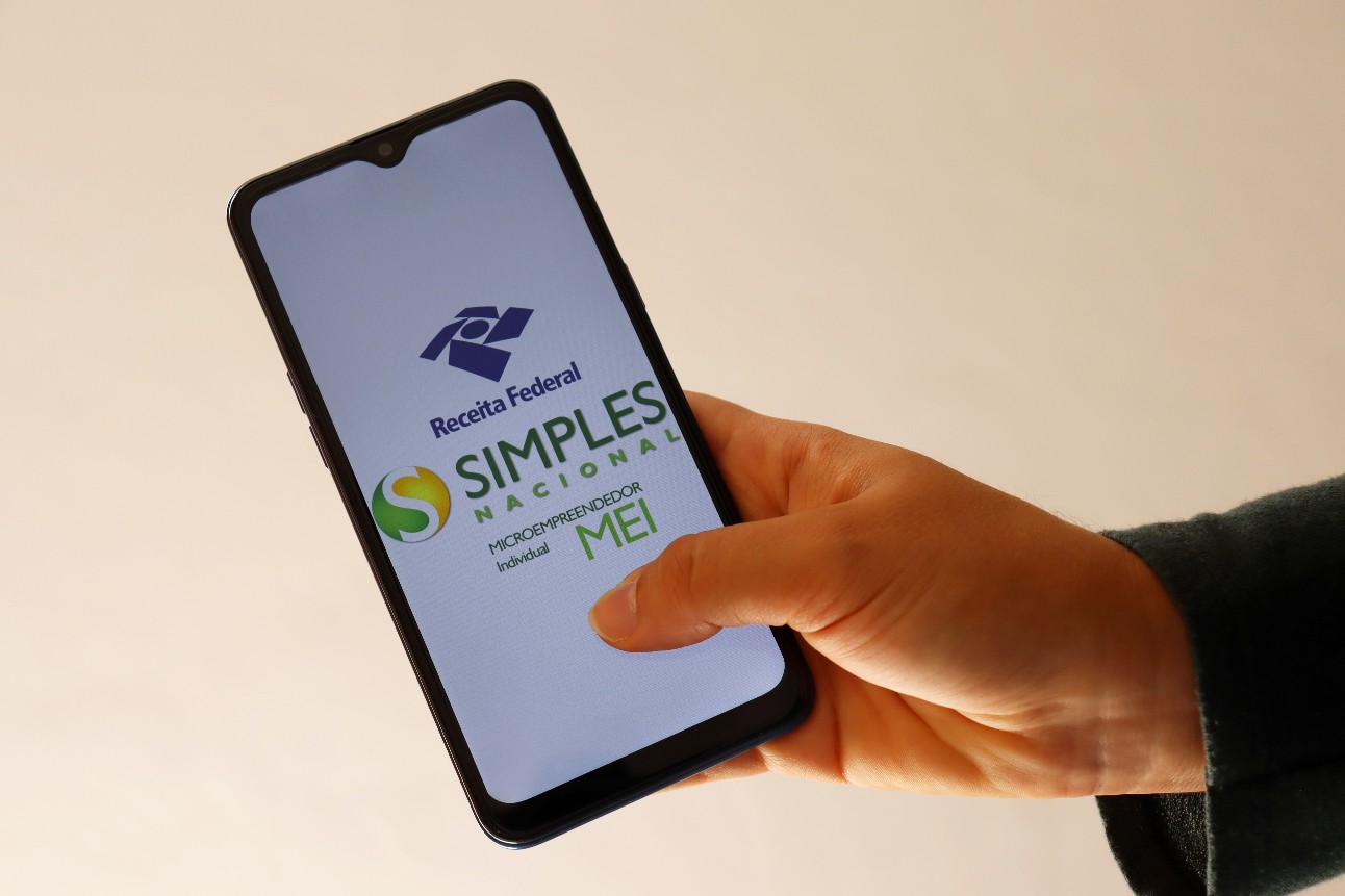 Pessoa segurando celular abrindo o aplicativo do Simples Nacional Pessoa segurando celular abrindo o aplicativo do Simples Nacional