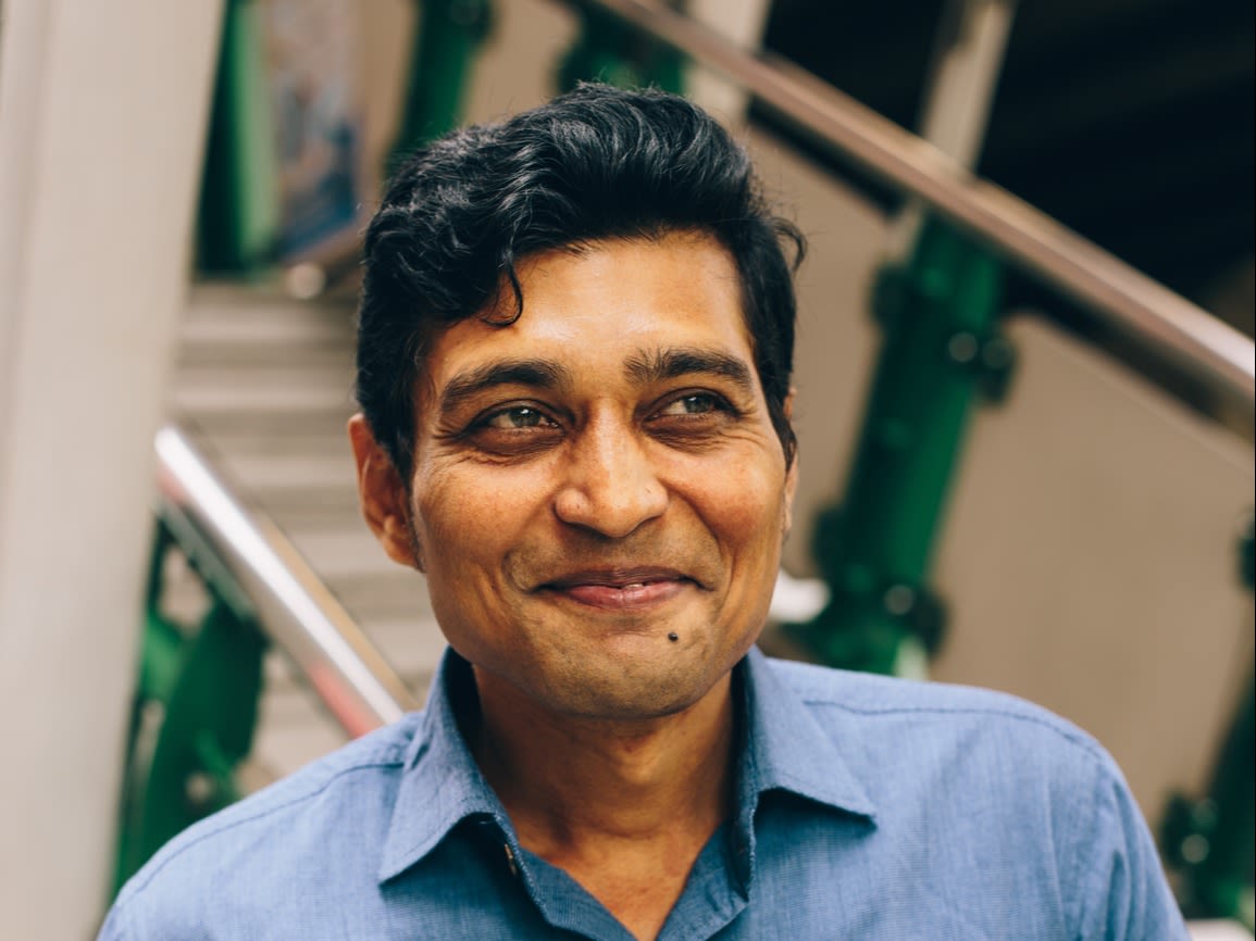 Smiling man with dark hair and a blue shirt.