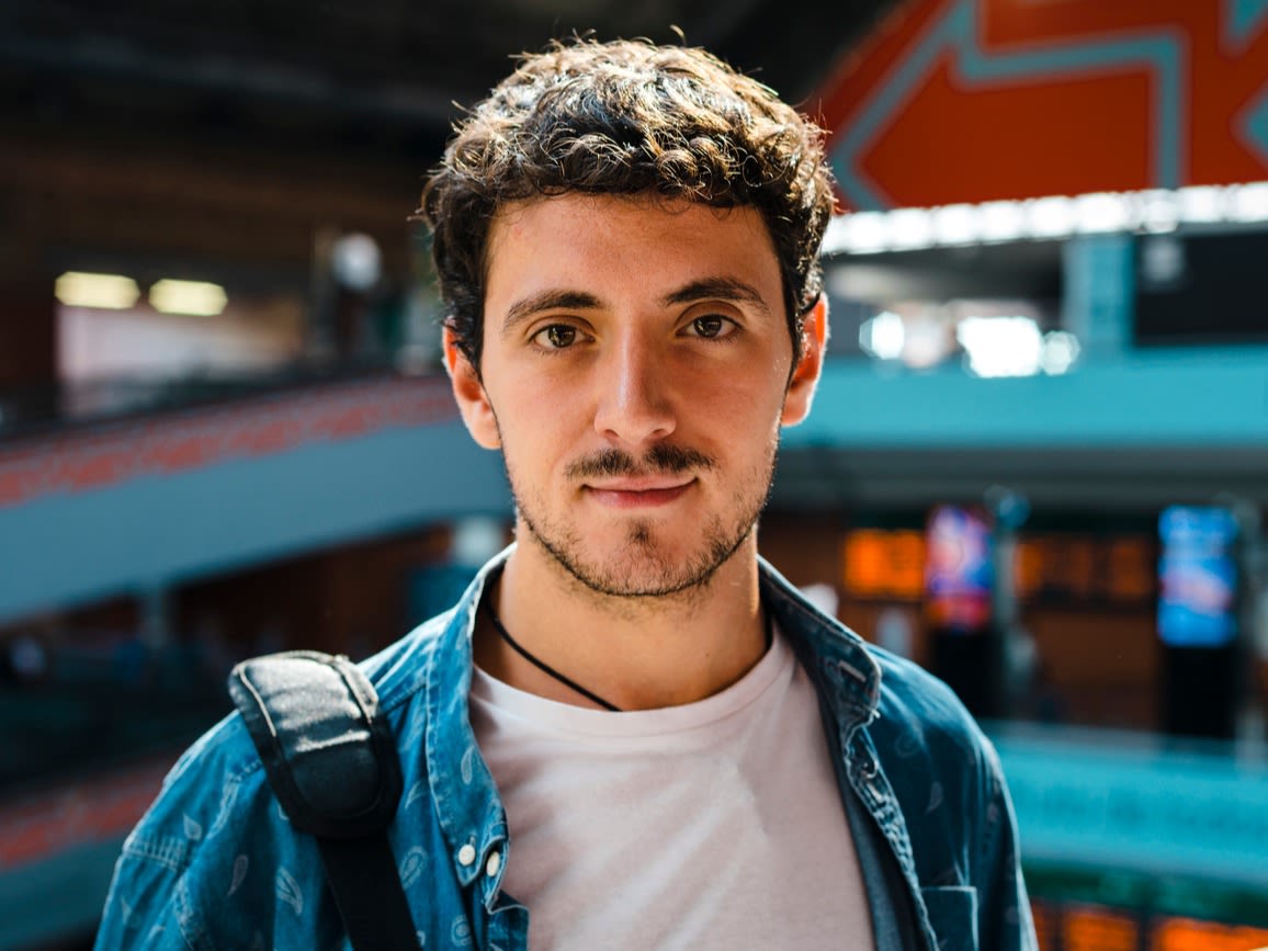 Male student wearing a blue shirt and carrying a bag.