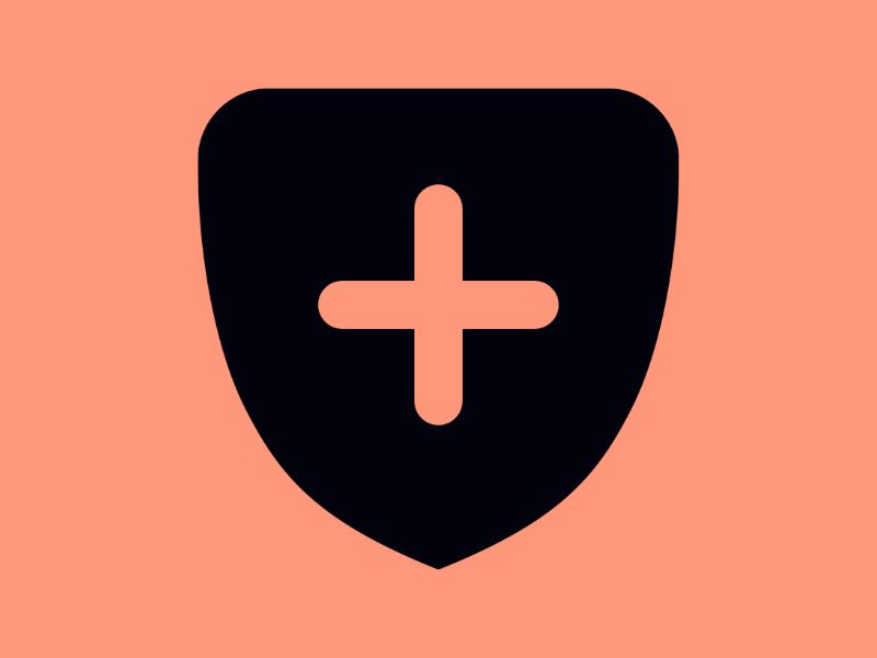A black shield on a peach background, with a peach cross in the middle of the shield.