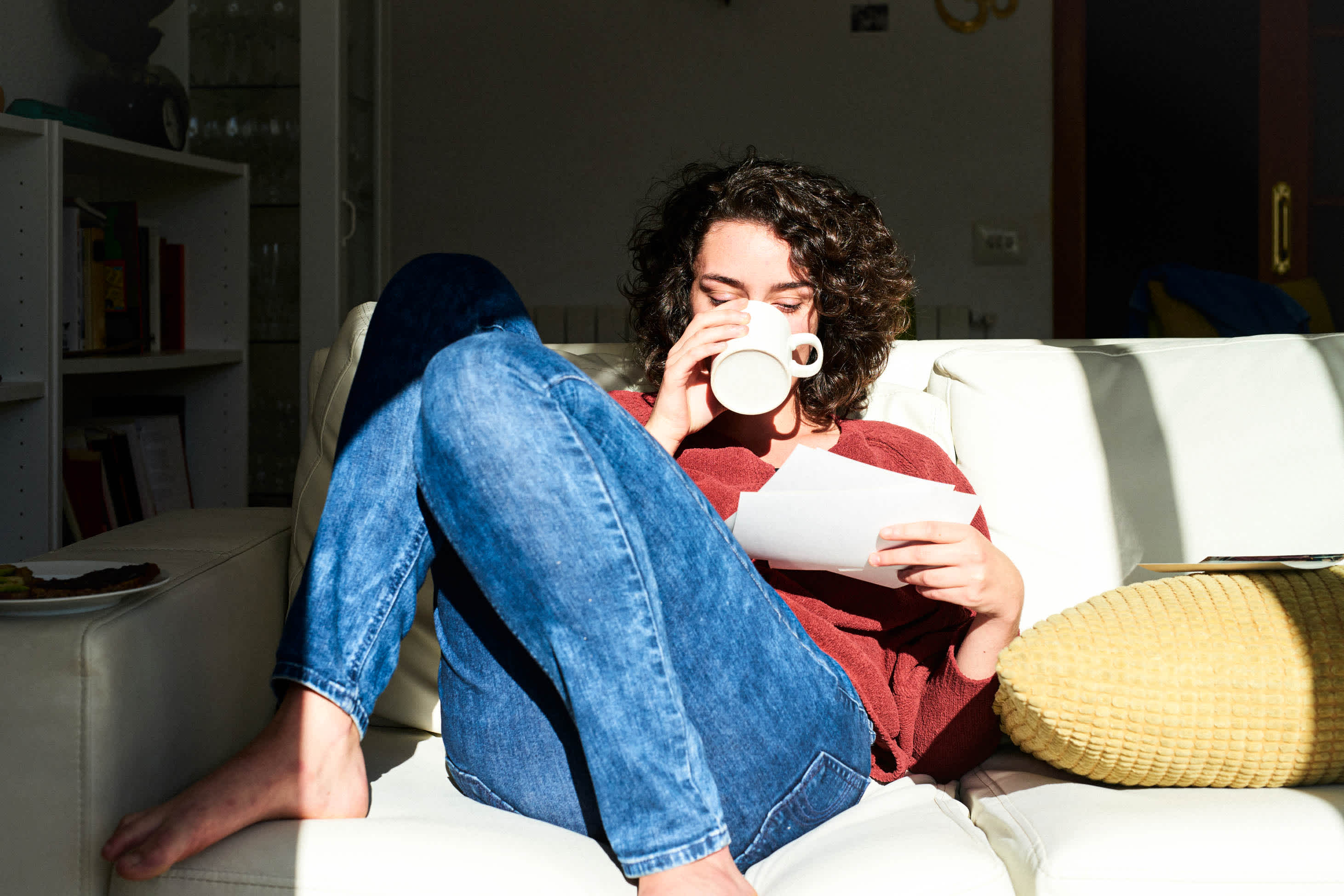 life insurance contestability period - woman drinking coffee on a couch while reading papers