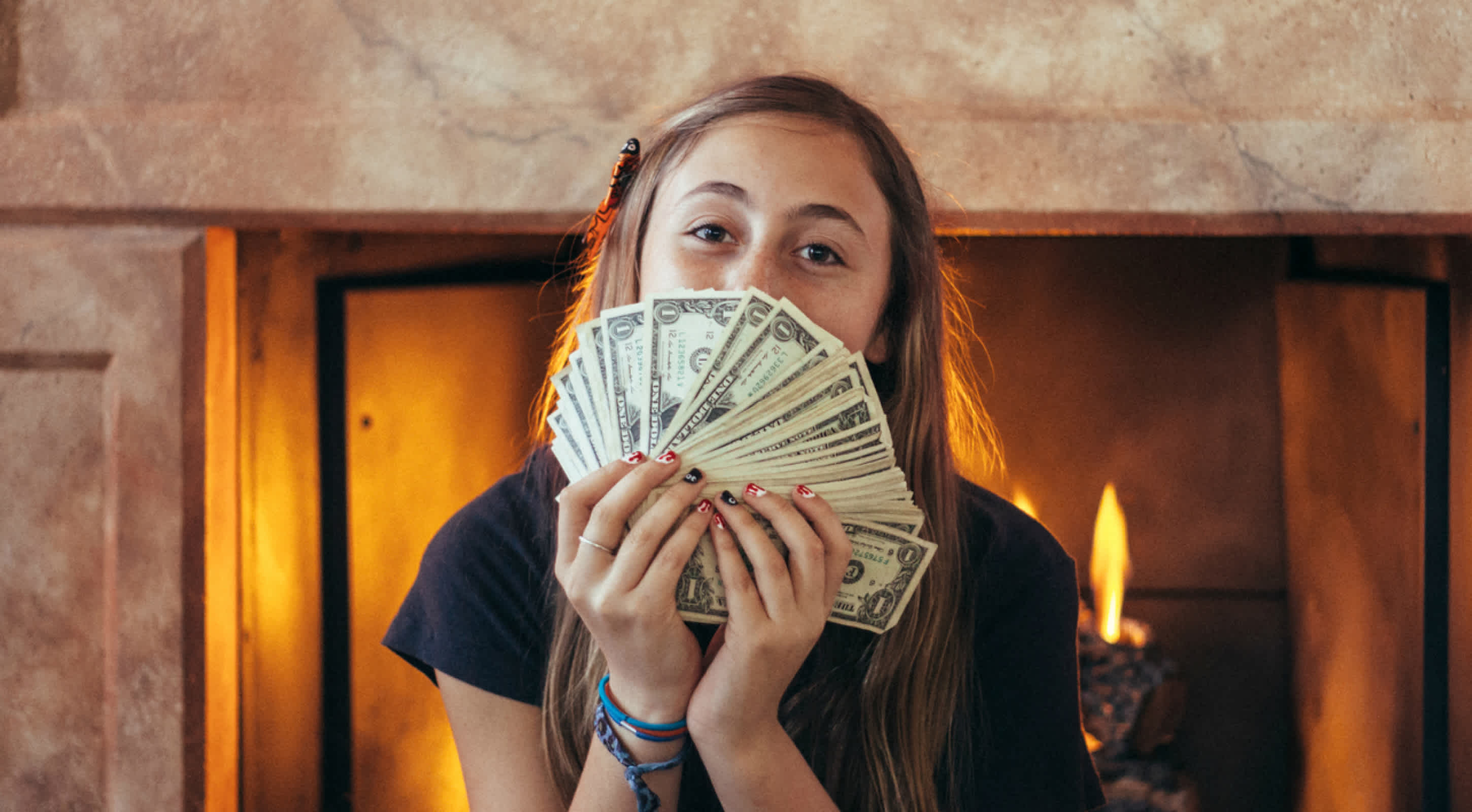 teenage girl holding money like a fan