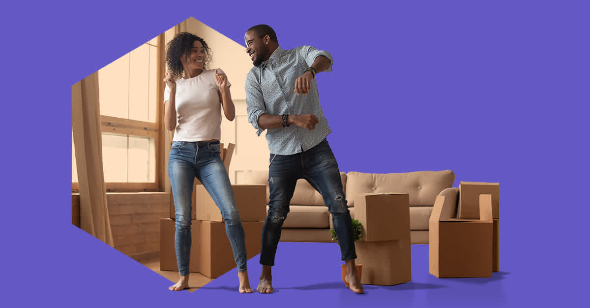 man and woman dancing amid boxes in living room - how buying a home changed my approach to money forever