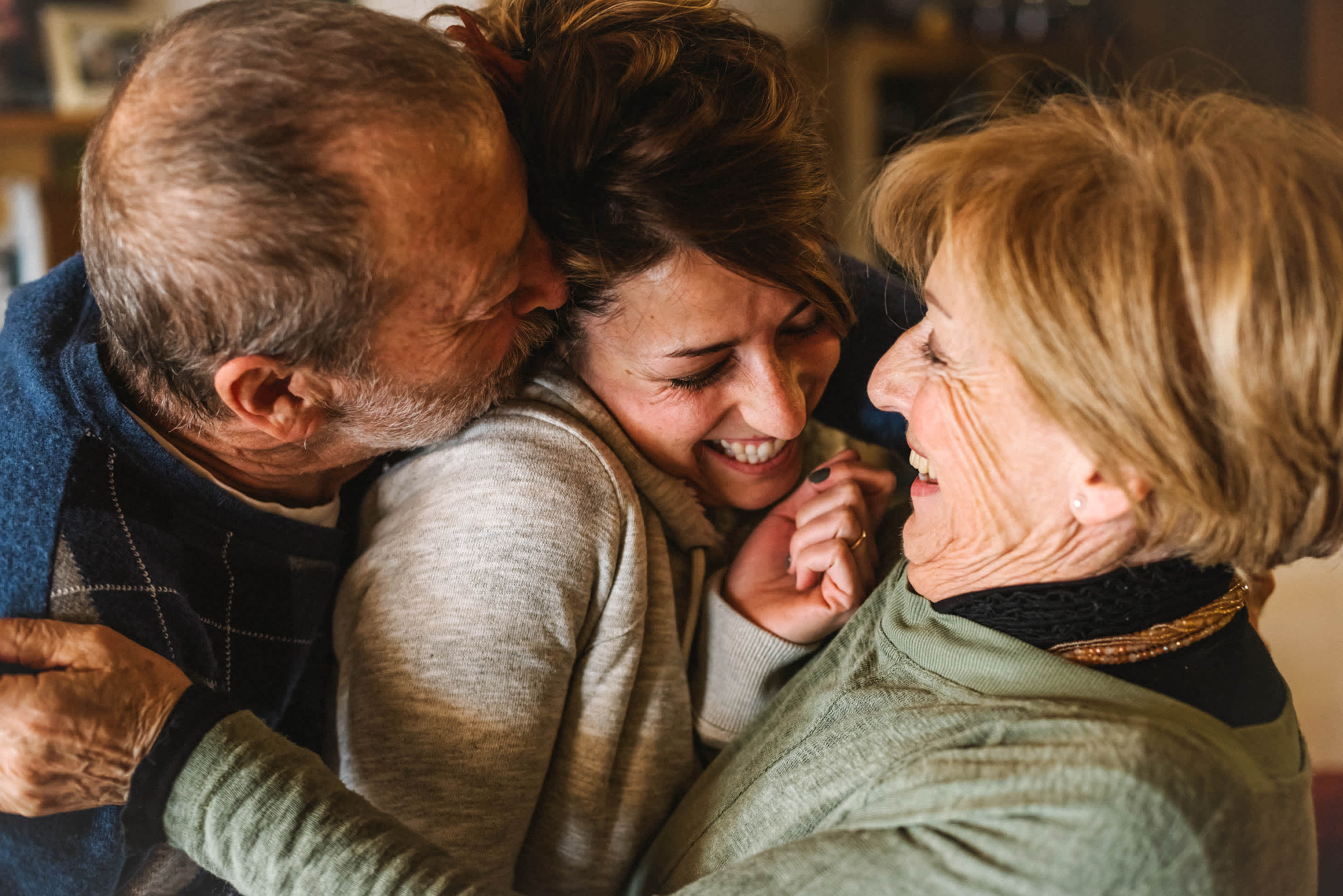 An older couple with their adult daughter laughing in a hug between them - different types of power of attorney