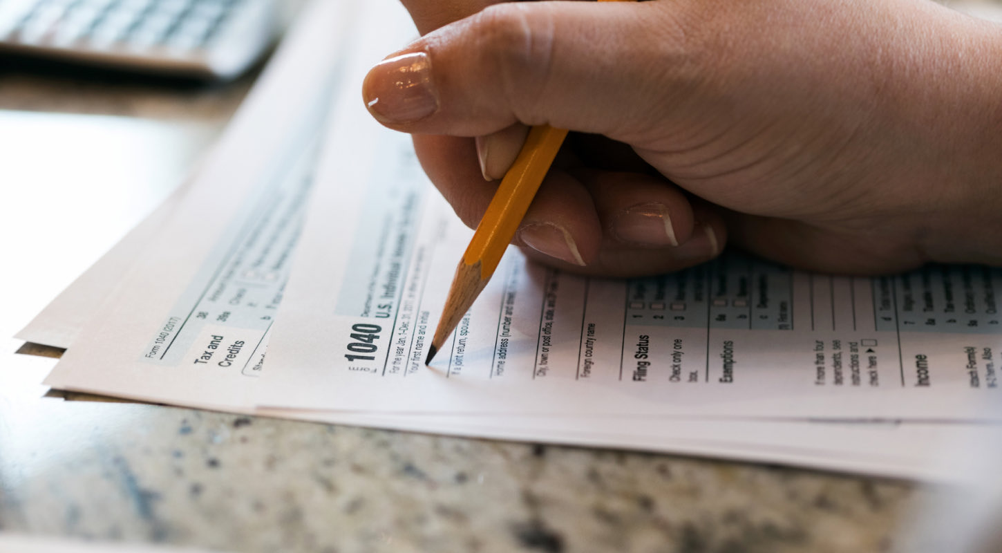 A US taxpayer fills out a 1040 tax form. 