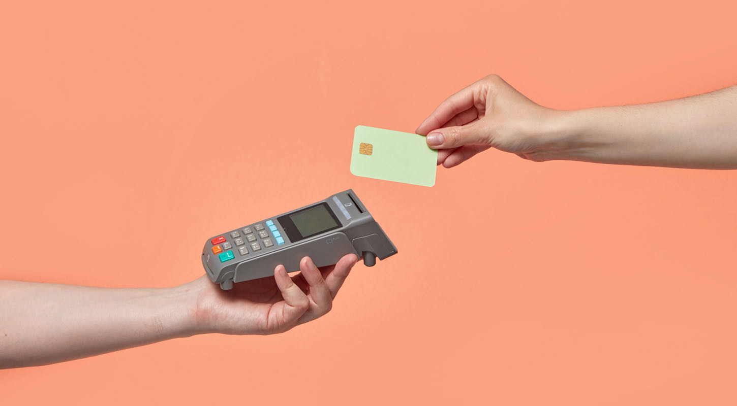 A credit card machine is held up, ready to accept a contactless payment.