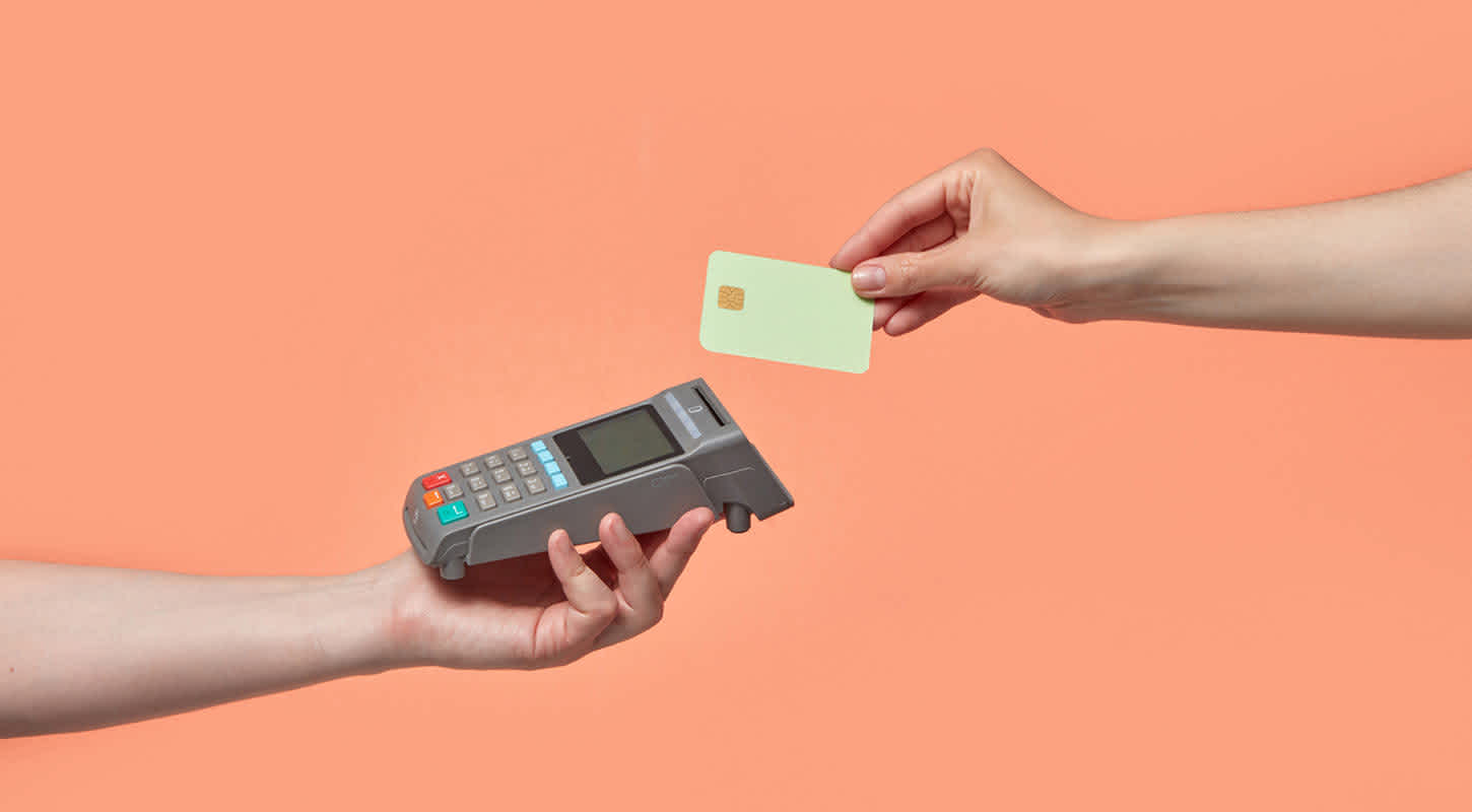 A credit card machine is held up, ready to accept a contactless payment.