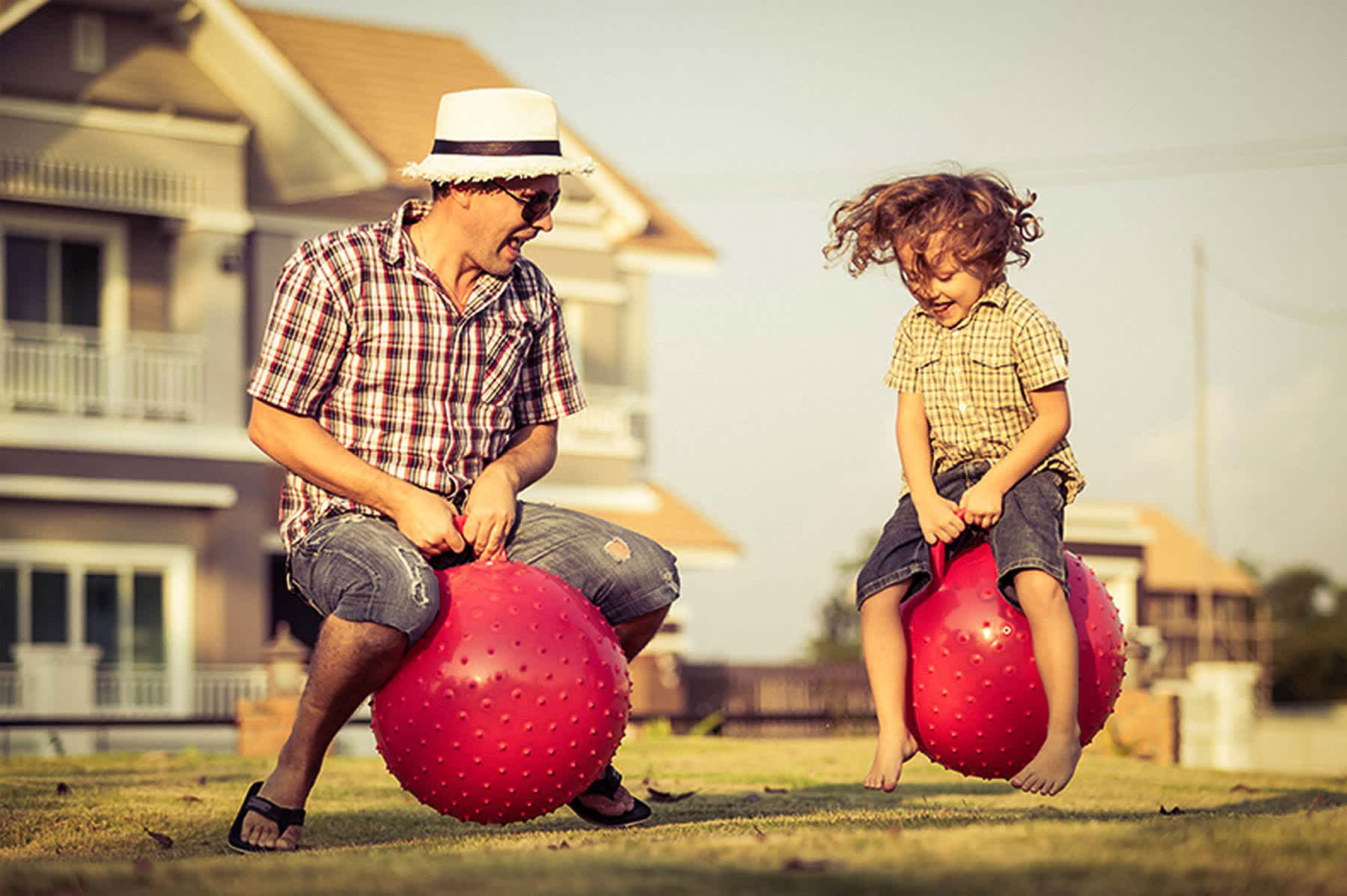 best cities for single parents - dad and child bouncing on yoga balls on suburban street