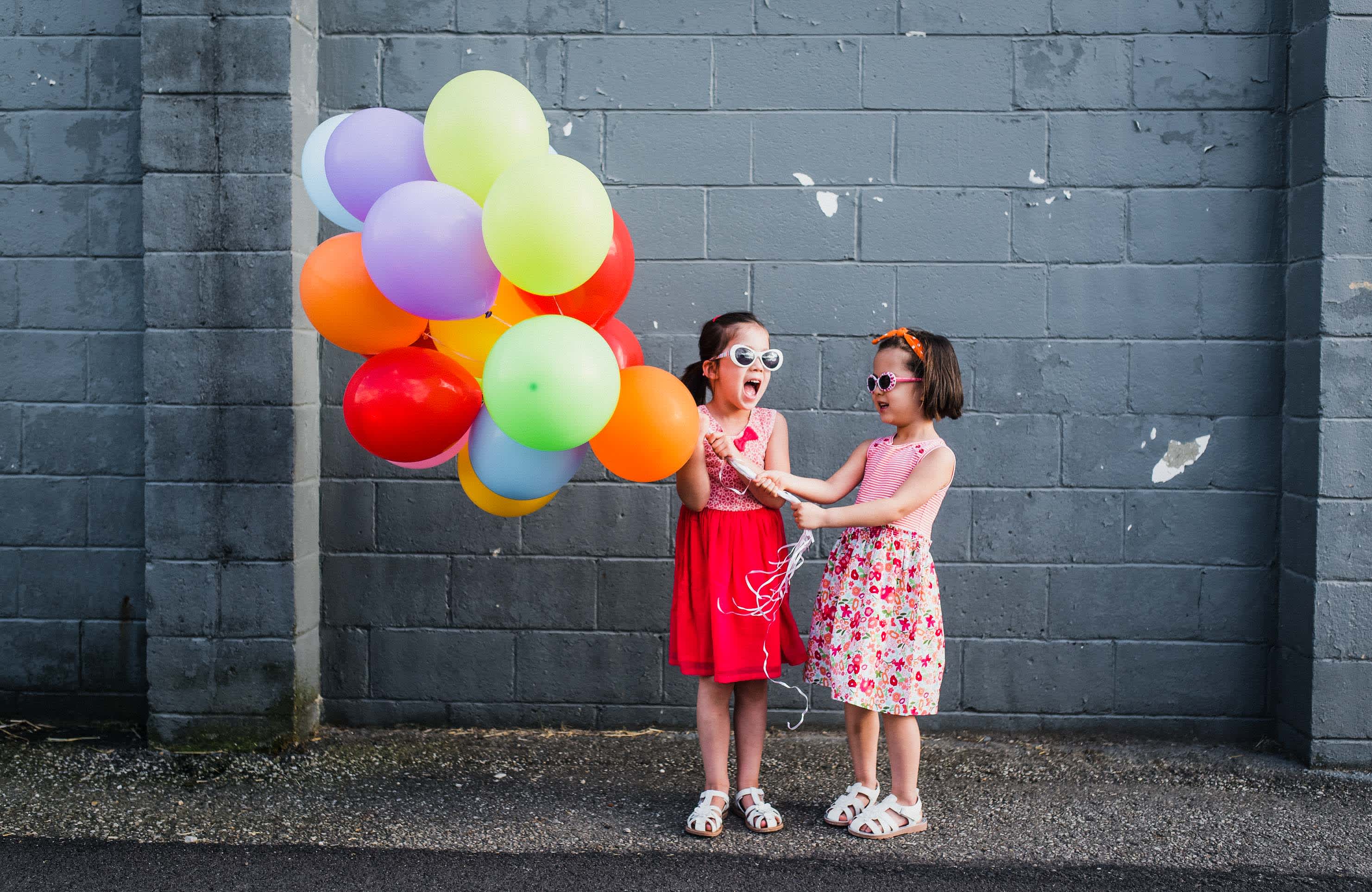 What to know about your kid at each age - two girls in sunglasses holding balloons