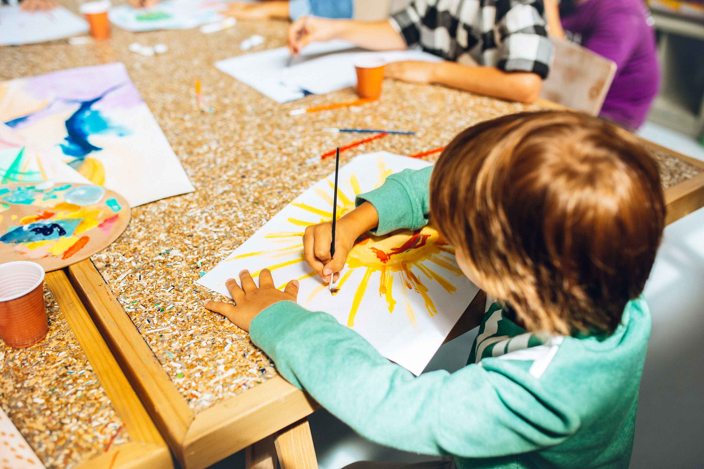 boy painting at a school table - states with the best public education