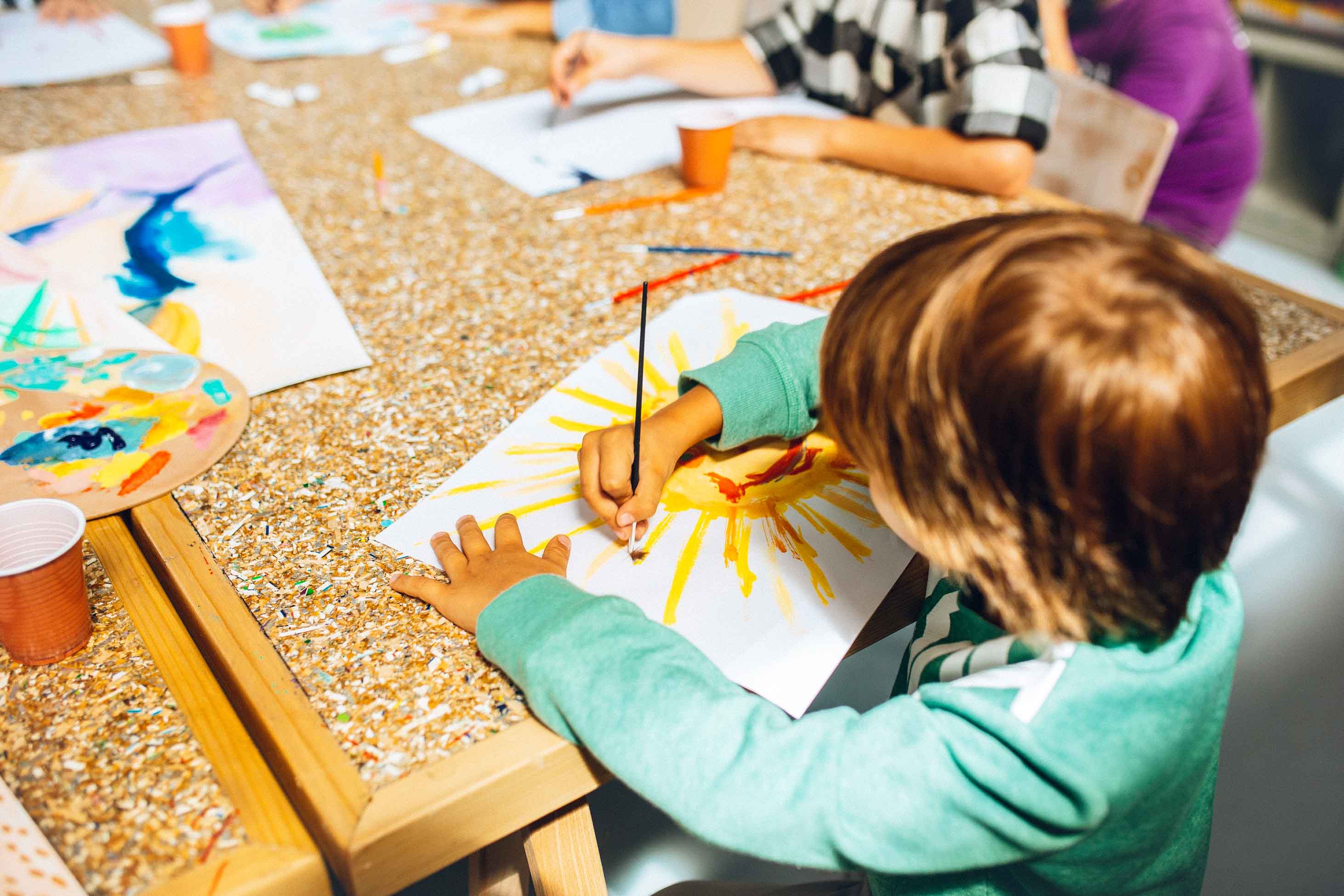 boy painting at a school table - states with the best public education
