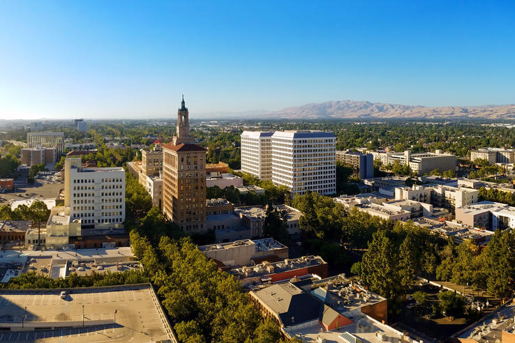 The Best-Paying Cities for Millennials - Mountain range, trees and buildings forming San Jose, California skyline. 