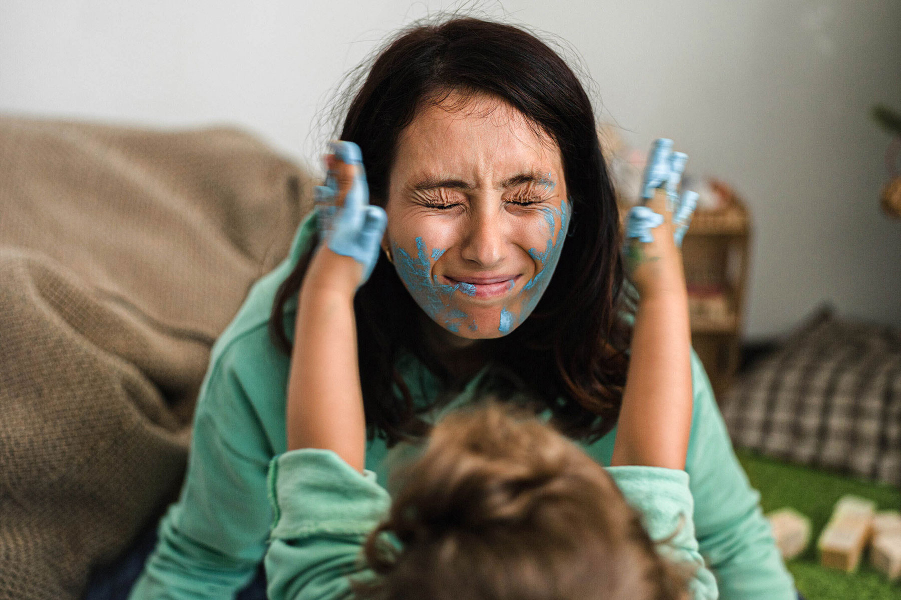 how real moms balance work and family - child with paint-covered hands putting paint on mom's face