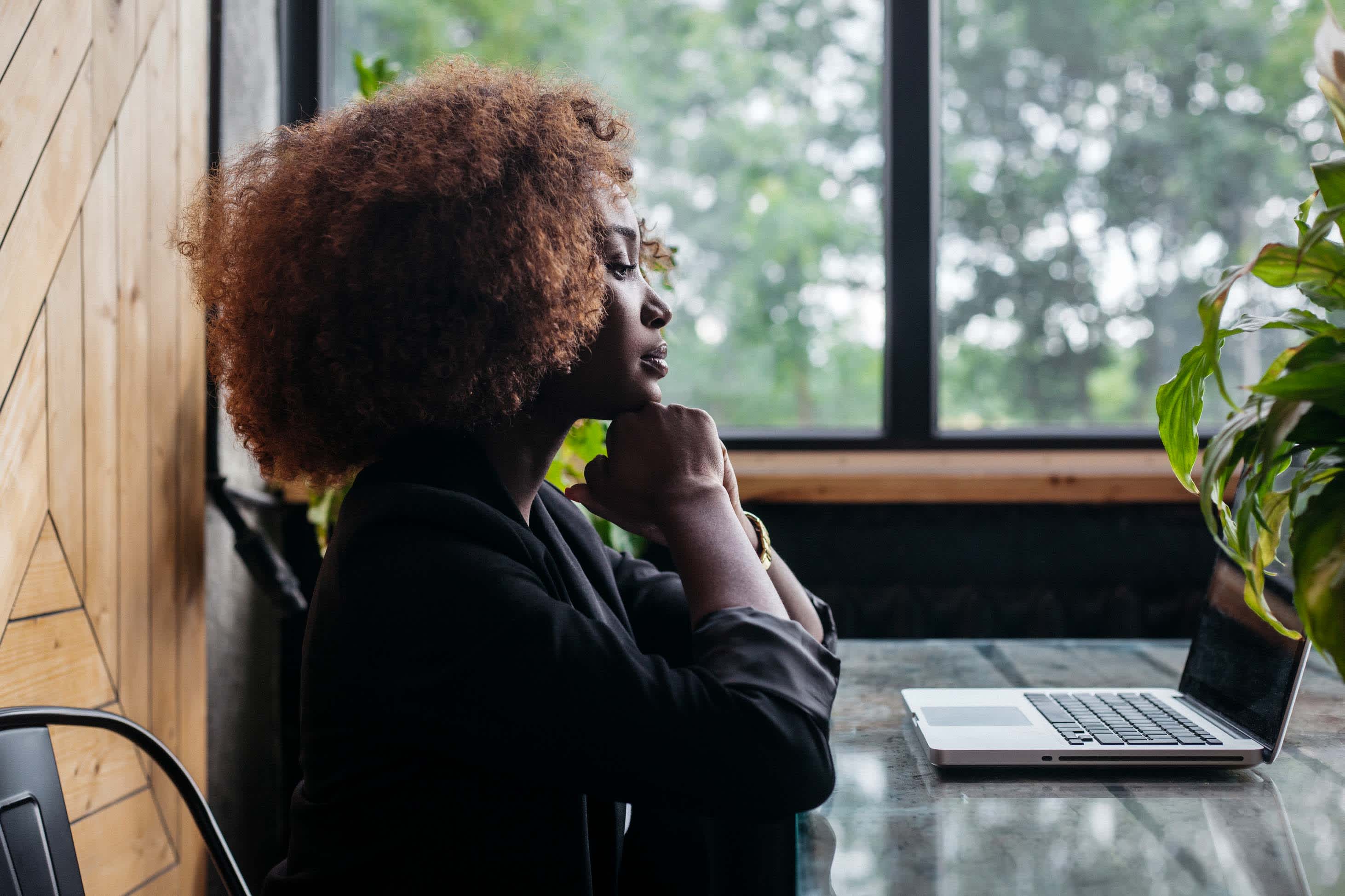 how becoming the breadwinner changed my view of money - woman looking contemplatively at computer, sitting by window