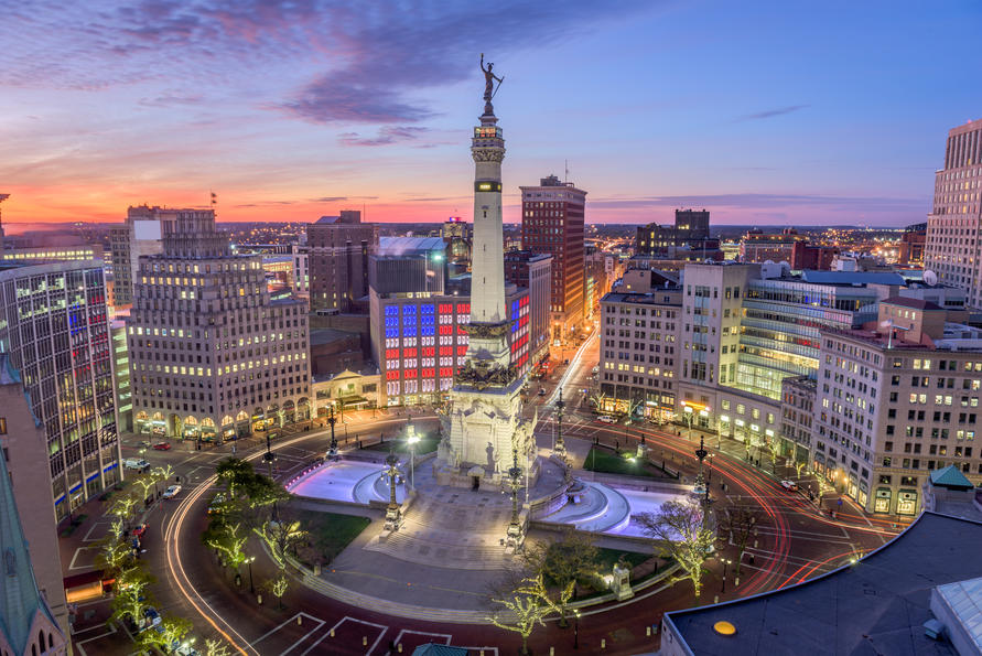 Cities With the Hardest-Working Parents - Indianapolis skyline at dusk with a panoramic view of the Indiana State Soldiers and Sailors Monument built on Monument Circle, a circular, brick-paved street that intersects Meridian and Market streets in the center of downtown.