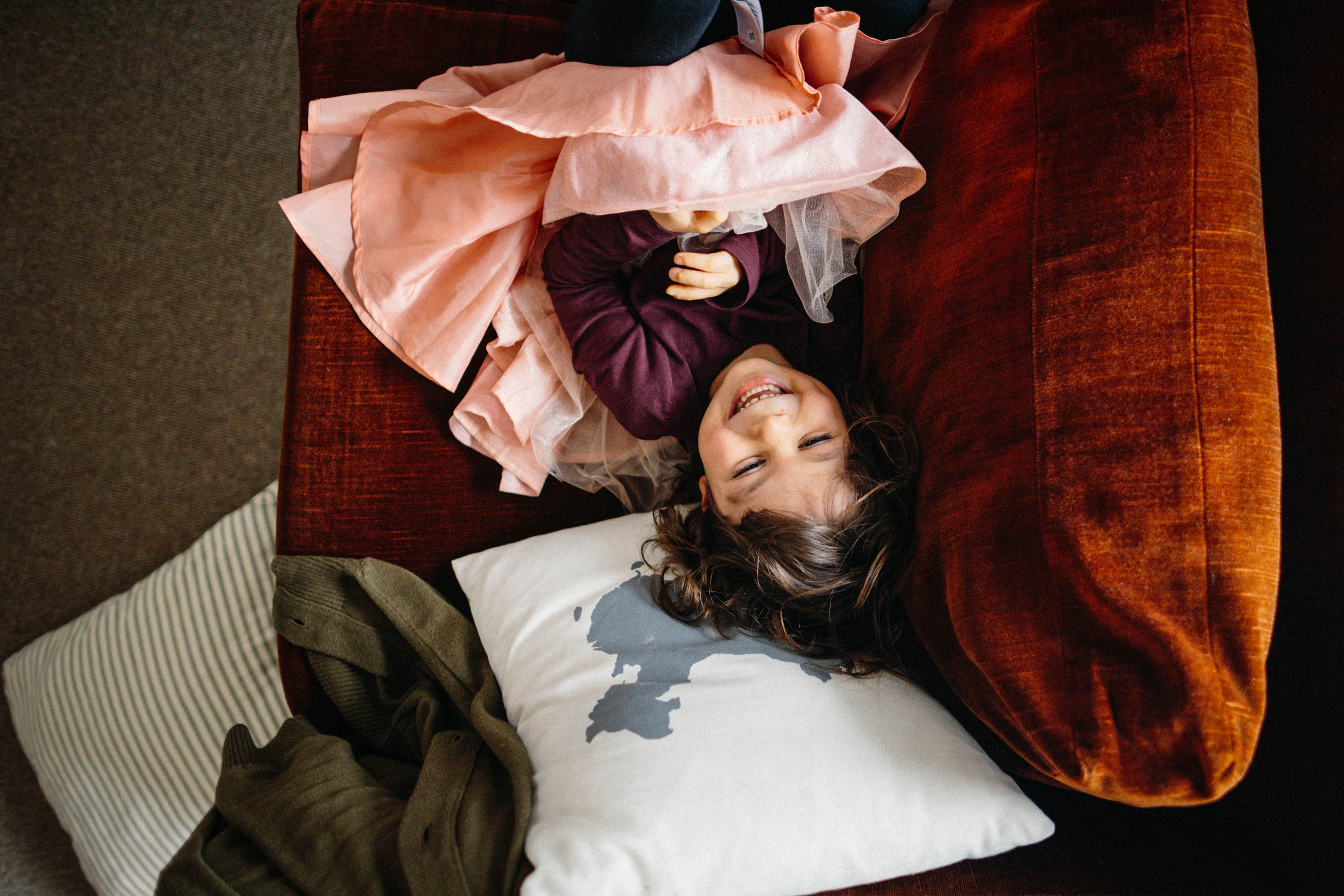 Girl in tutu laughing on a couch - the most rewarding things about parenthood