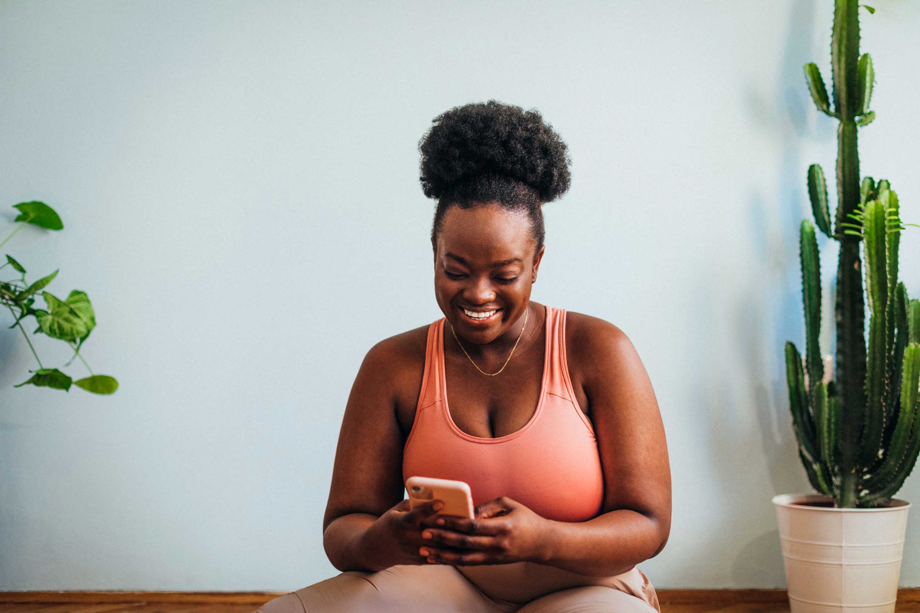 can you get life insurance if you're overweight? - a woman in a yoga studio smiling and looking at her phone