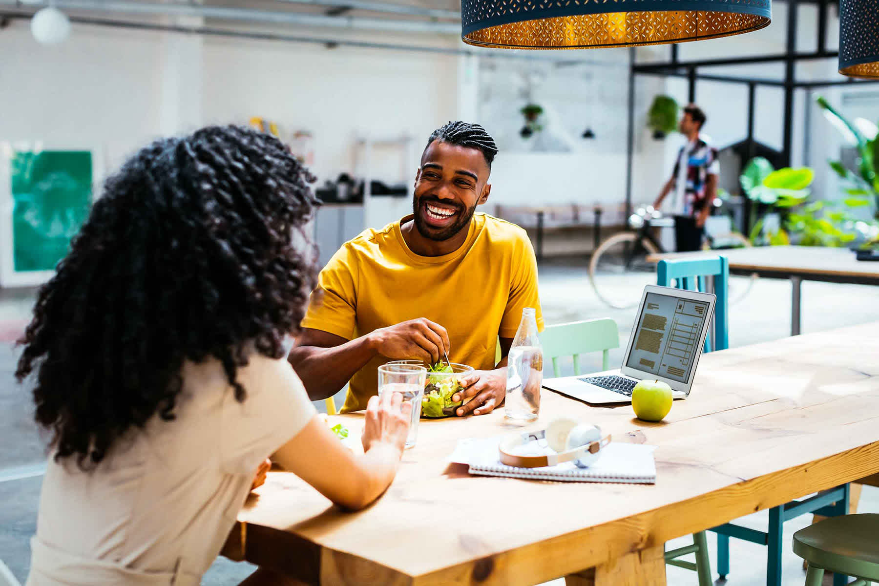 10 money moves you can do today - man and woman at a large table with a laptop eating lunch