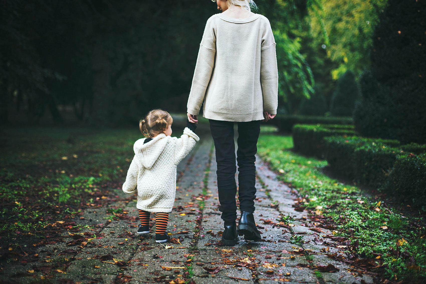 how to choose a legal guardian in your will - woman holding toddler girl's hand outside on path
