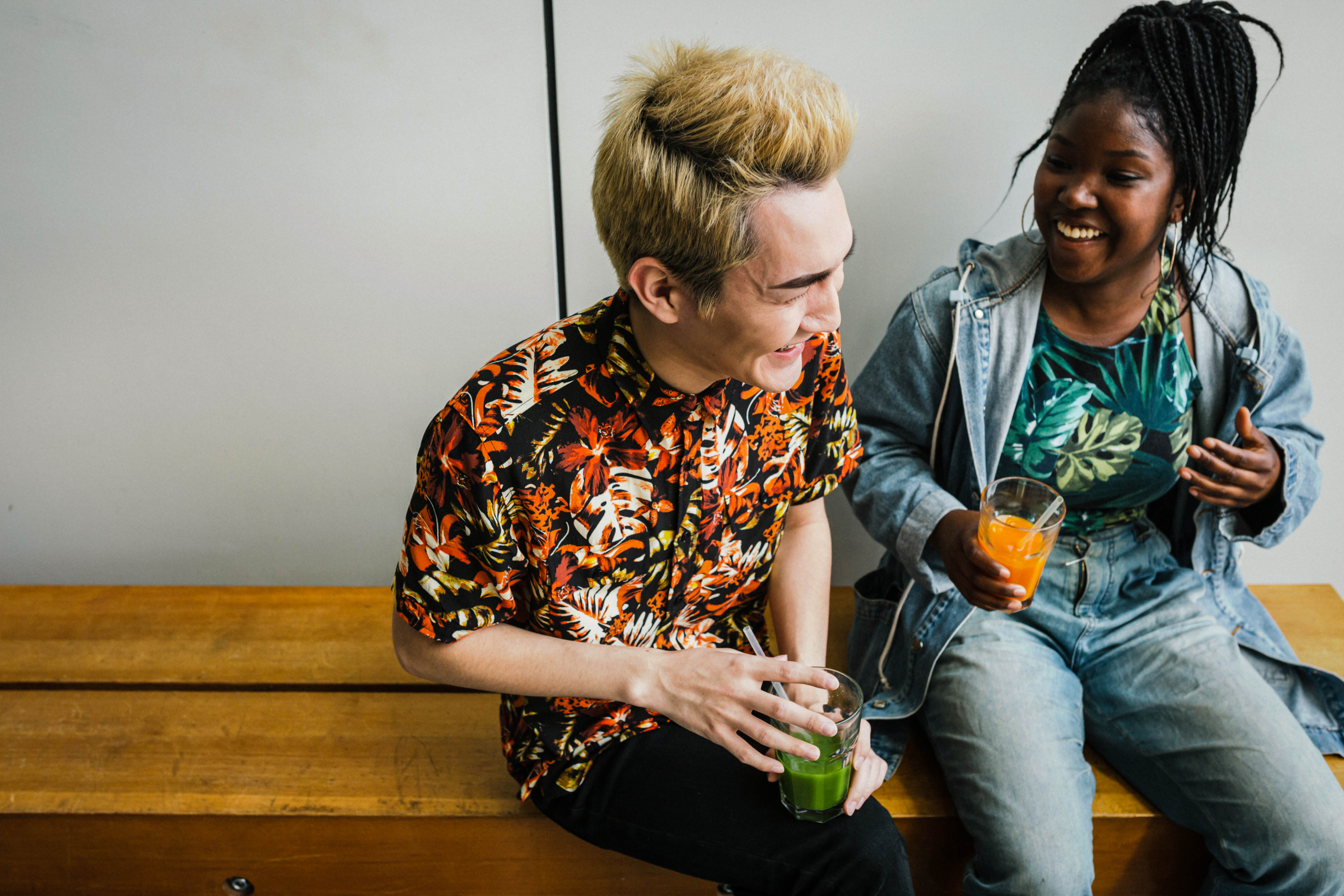 life insurance for millennials - a young man and a young woman laughing while drinking smoothies on a bench