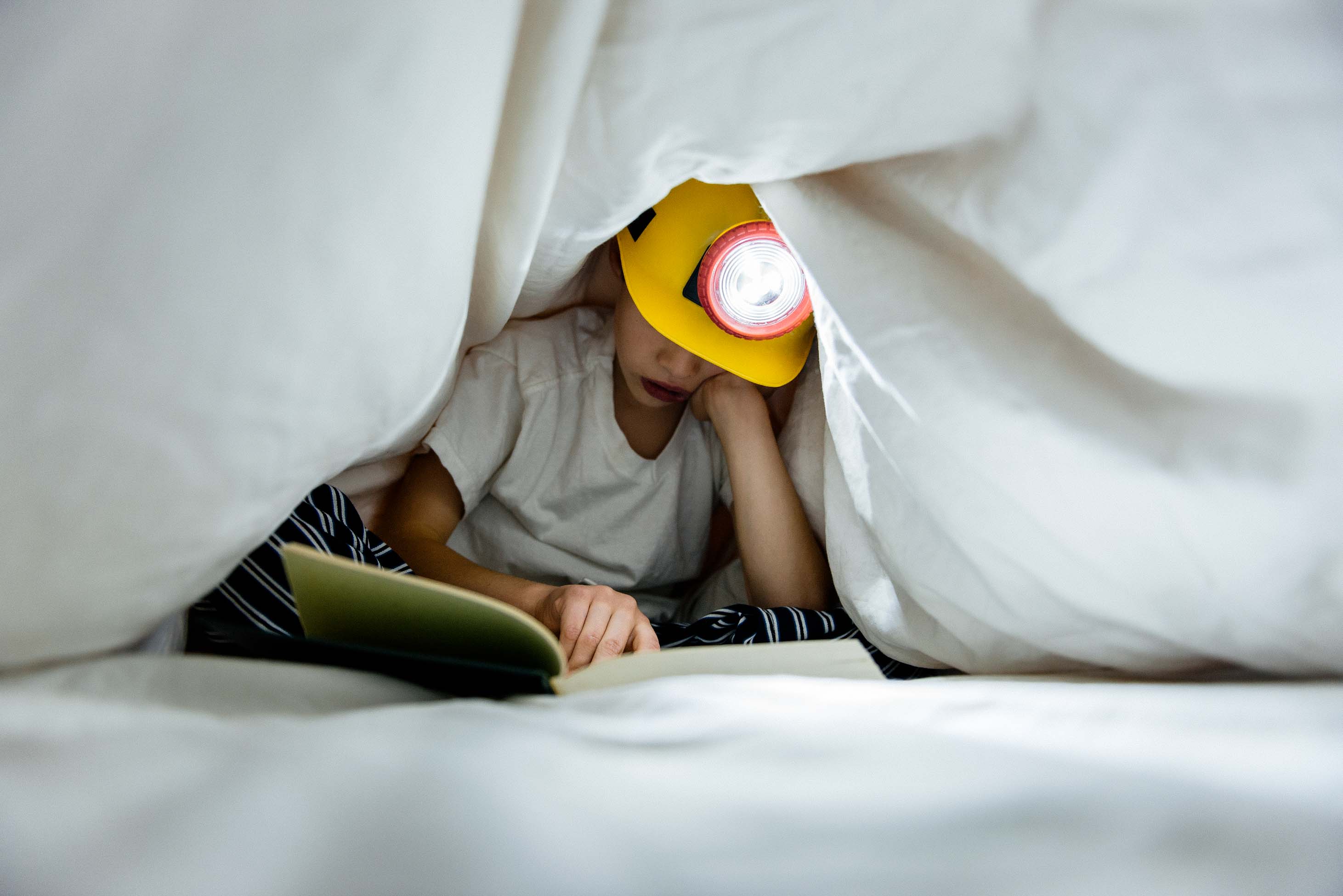 what to now when you have an 8 year old - kid wearing a headlamp and reading under covers