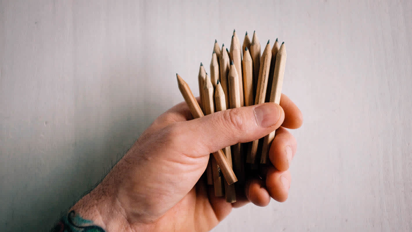 A handful of wooden mini pencils are gently held in a man's hand.