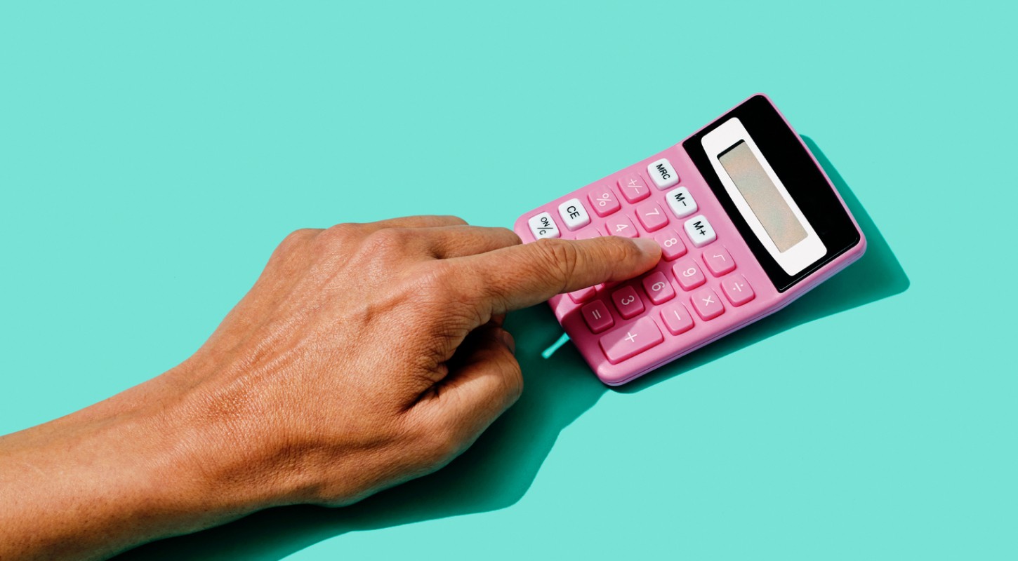 An outstretched hand presses the buttons of a pink calculator, representing the process of determining how much life insurance someone can afford.