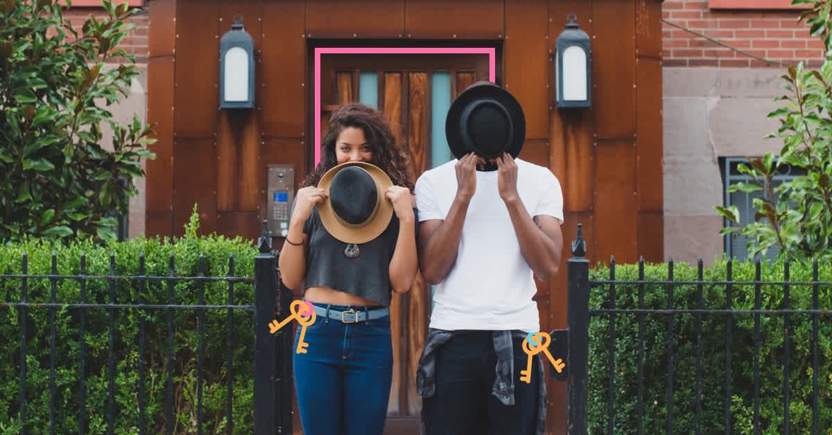 man and woman playing with fedoras in front of a house - tips for buying your first home