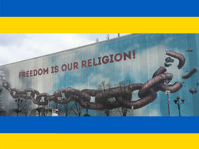 Large mural painting of a breaking chain with the slogan "Freedom is our religion" written above it.
