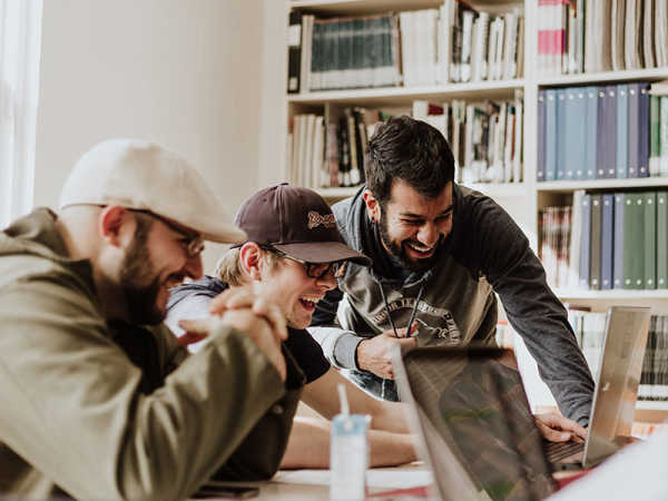 Work colleagues laughing at something on a laptop