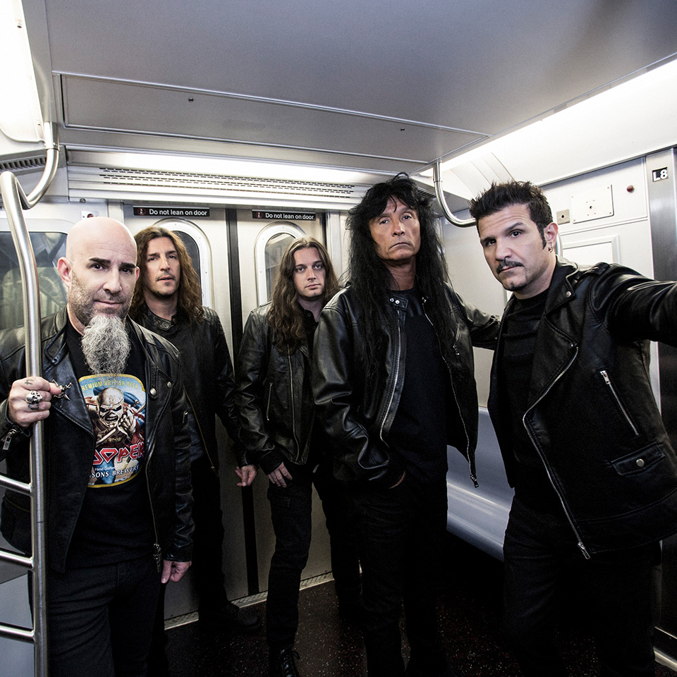 Fem män i svarta skinnjackor står i en tunnelbanevagn och poserar för kameran med allvarliga ansiktsuttryck.