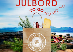 A paper bag labeled "Tyrols Vilda Julbord" contains cheese, sausage, and herbs with a holiday picnic background and the text "Julbord to go-ho-ho-ho.