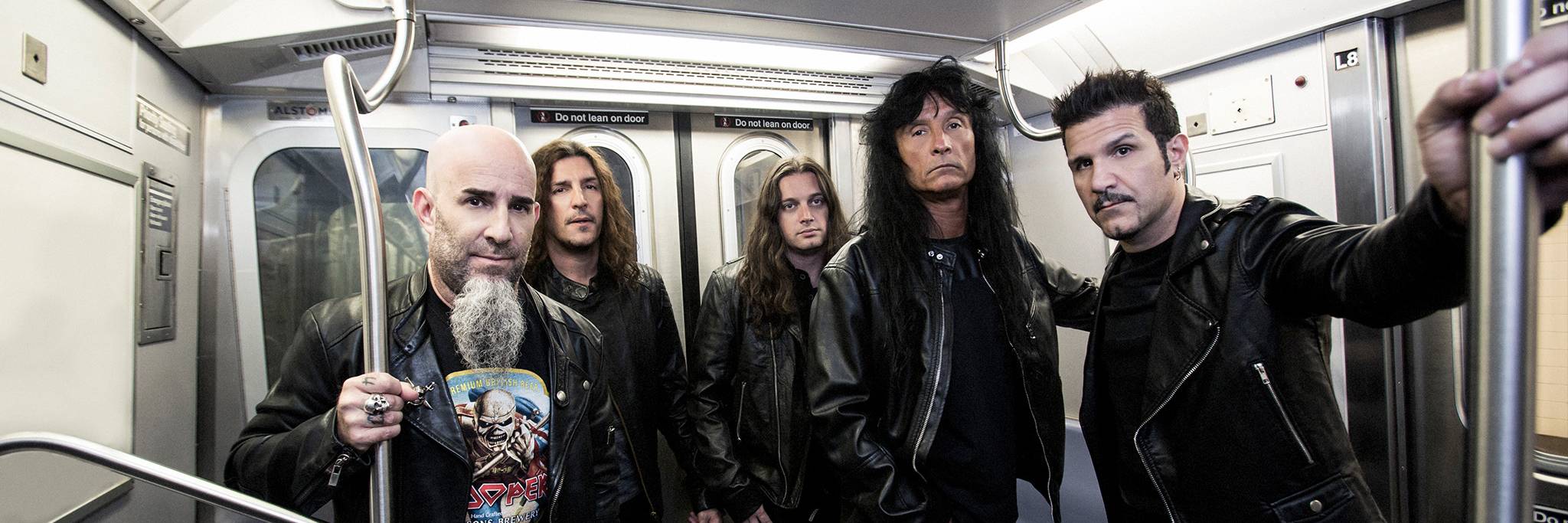 Fem män i svarta skinnjackor står i ett tunnelbanetåg, håller i ledstängerna och tittar in i kameran.