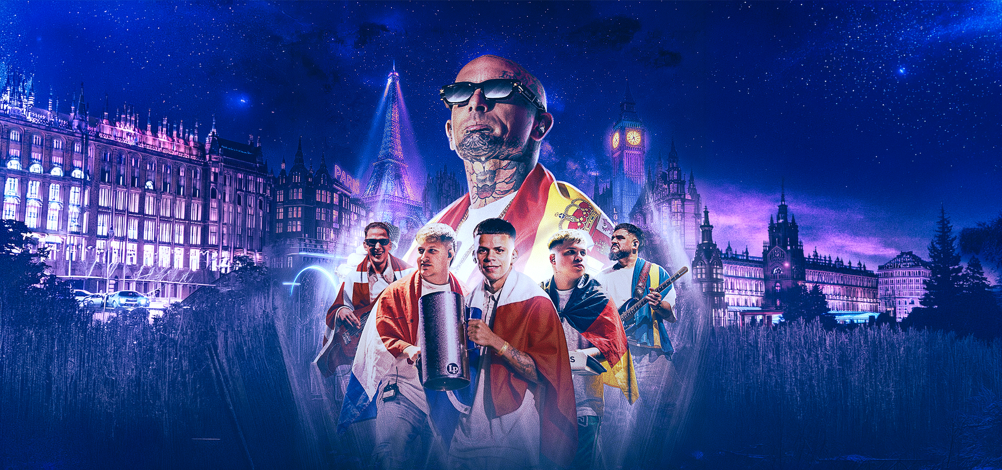 A group of men, some holding musical instruments and draped in flags, stand in front of city landmarks at night with a blue and purple sky in the background.