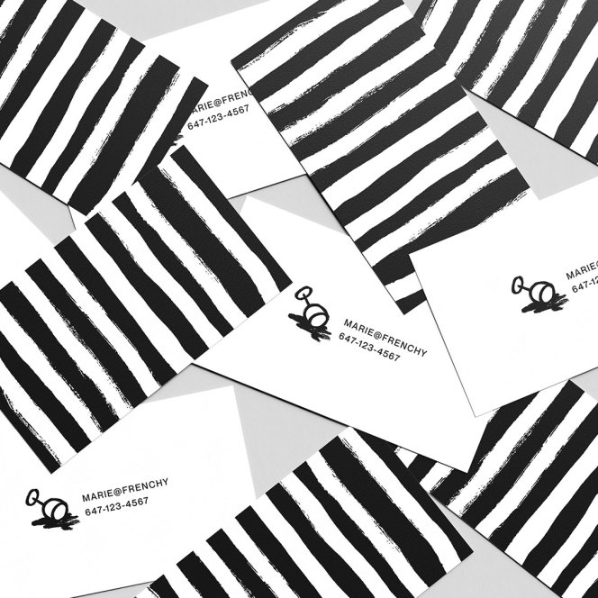Frenchy business cards scattered on a surface - the back featured the Frenchy striped pattern, the front featuring the wineglass illustration and some contact information.