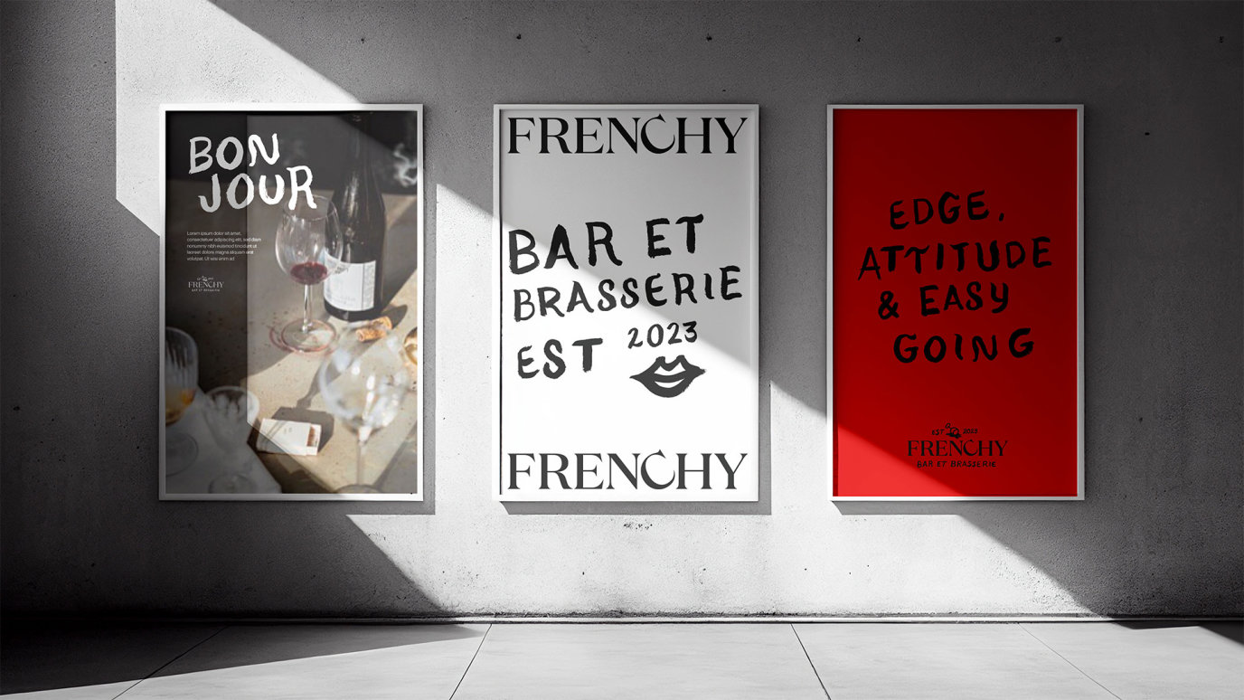 Three framed Frenchy posters on a concrete wall.