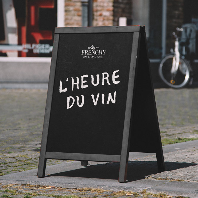 A sandwich board reading "l'heure du vin" in the Frenchy hand paint font, with Frenchy logo lockup. 