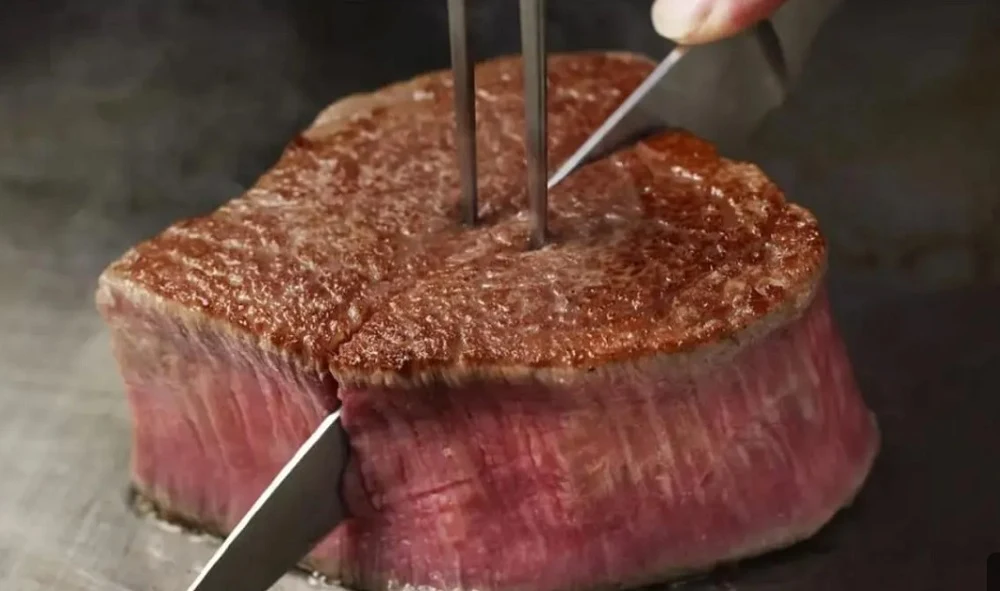 Steak being sliced with a knife on a griddle -pelago