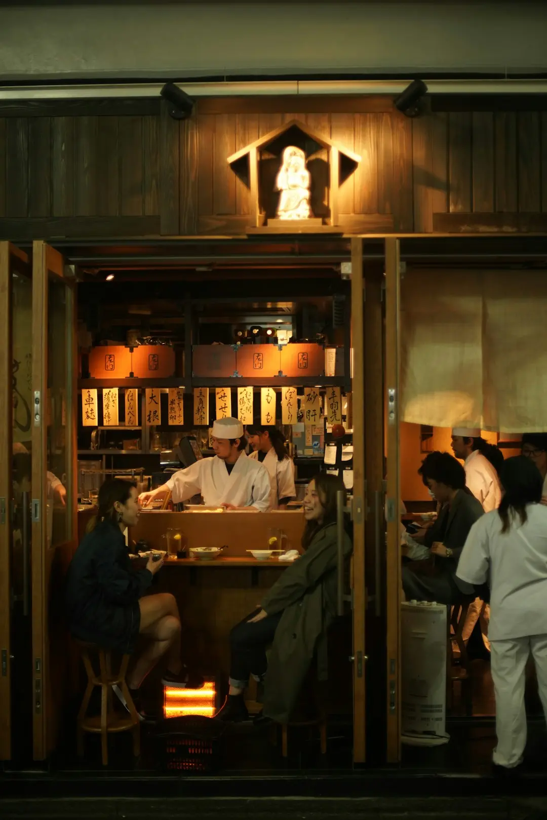 People enjoying drinks in a Japanese bar as a server attends to them