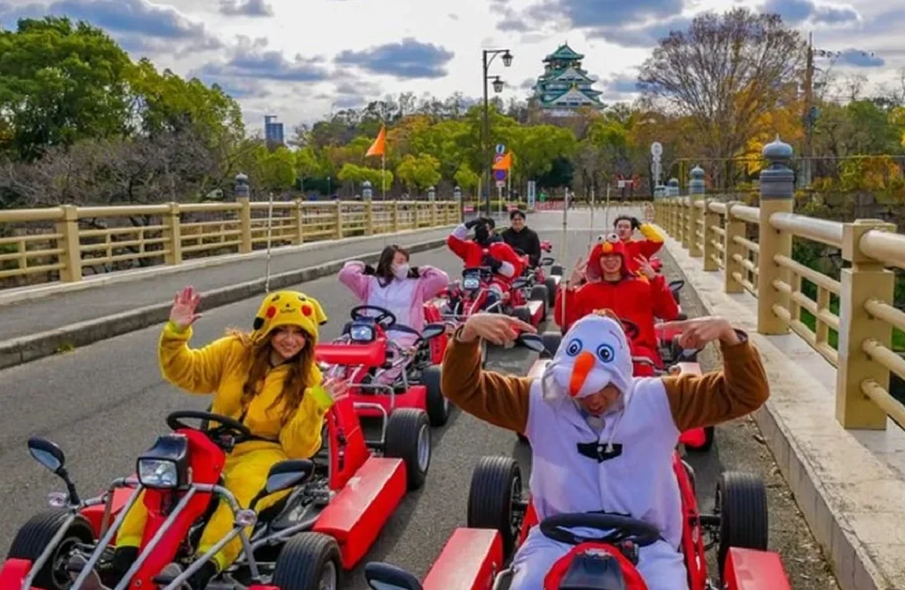 A group of people posing in costumes while indulging in go karting in Osaka with the Osaka Castle in the backdrop | Non Touristy Things to Do in Osaka