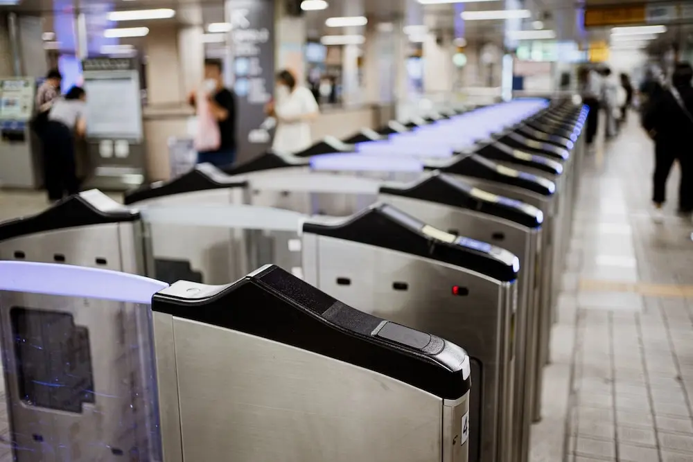 Ticket gantries at a busy Seoul train station with commuters walking in the background.