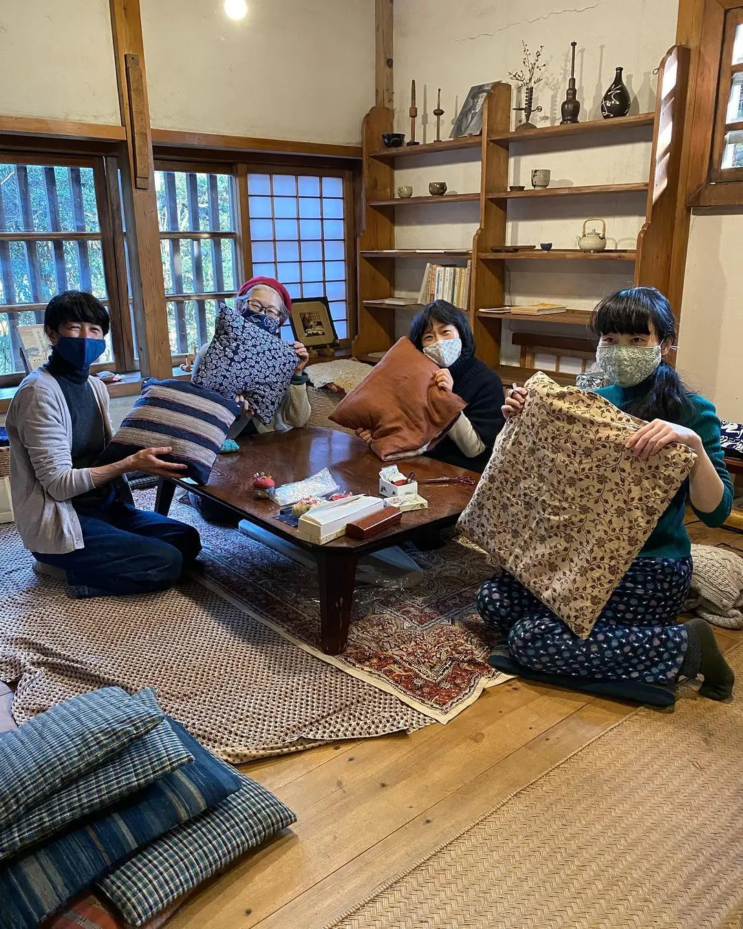 Four people showing off their zabuton after indulging into the Japanese traditional pillow-making art class in Tokyo.